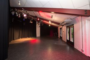 Studio with natural light and lighting rig and black floor.